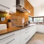 Brick wall in spacious modern designed white kitchen with marble floor