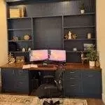a desk with a computer and shelves in a room