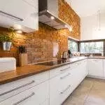 a kitchen with brick wall and white cabinets